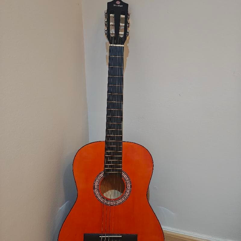 Unistar classic guitar with a stand and two picks